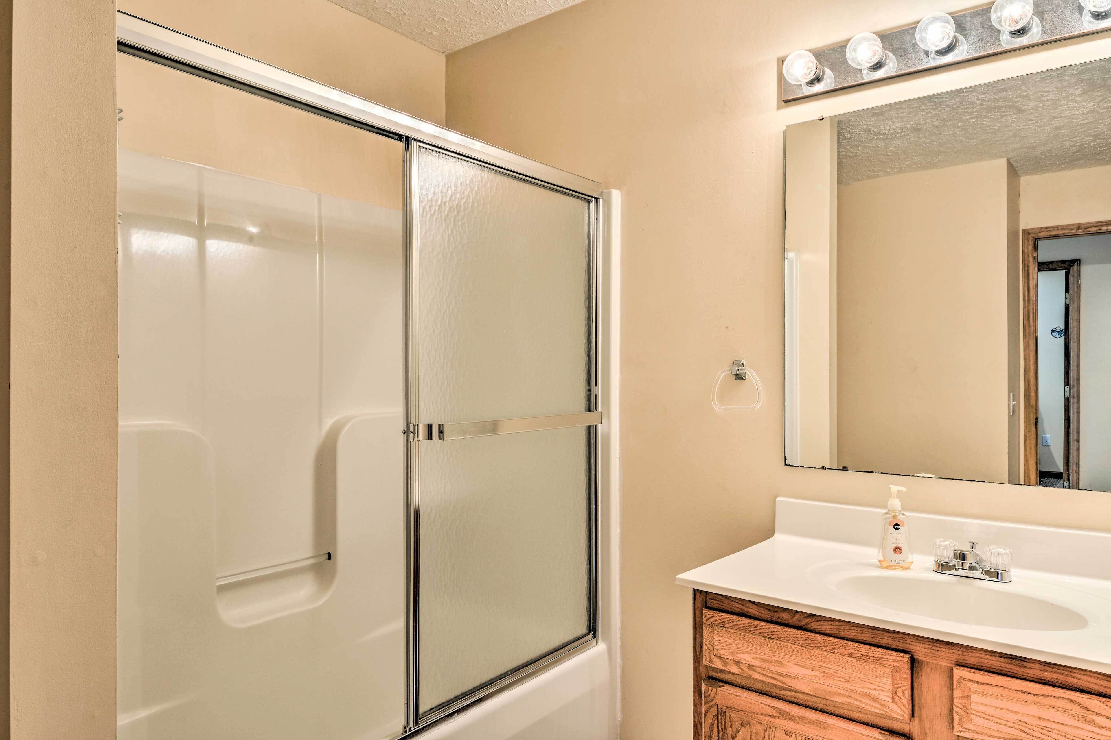 A bathroom with a glass shower enclosure, a vanity with a mirror, and a sink.