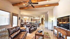 A spacious living room with leather sofas, a wooden coffee table, and a ceiling fan. - Scottsdale Home: Pickleball, Heated Pool & Hot Tub (Scottsdale)