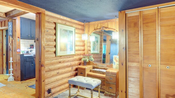 A log cabin interior with a wooden bench, dresser, mirror, and a door labeled 'CABIN.' - Lake Lure Home w/ Deck: At Lake Lure & Golf! (Lake Lure)