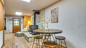 A room with a stone wall, a round table with stools, a fireplace, a lamp, and a sign that says 'coffee welcome.' - Lake Lure Home w/ Deck: At Lake Lure & Golf! (Lake Lure)