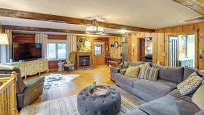A cozy living room with a large sectional sofa, a television, wooden walls, and a fireplace. - Lake Lure Home w/ Deck: At Lake Lure & Golf! (Lake Lure)