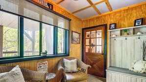 A cozy room with wicker furniture, a bench, and a wooden door. - Lake Lure Home w/ Deck: At Lake Lure & Golf! (Lake Lure)
