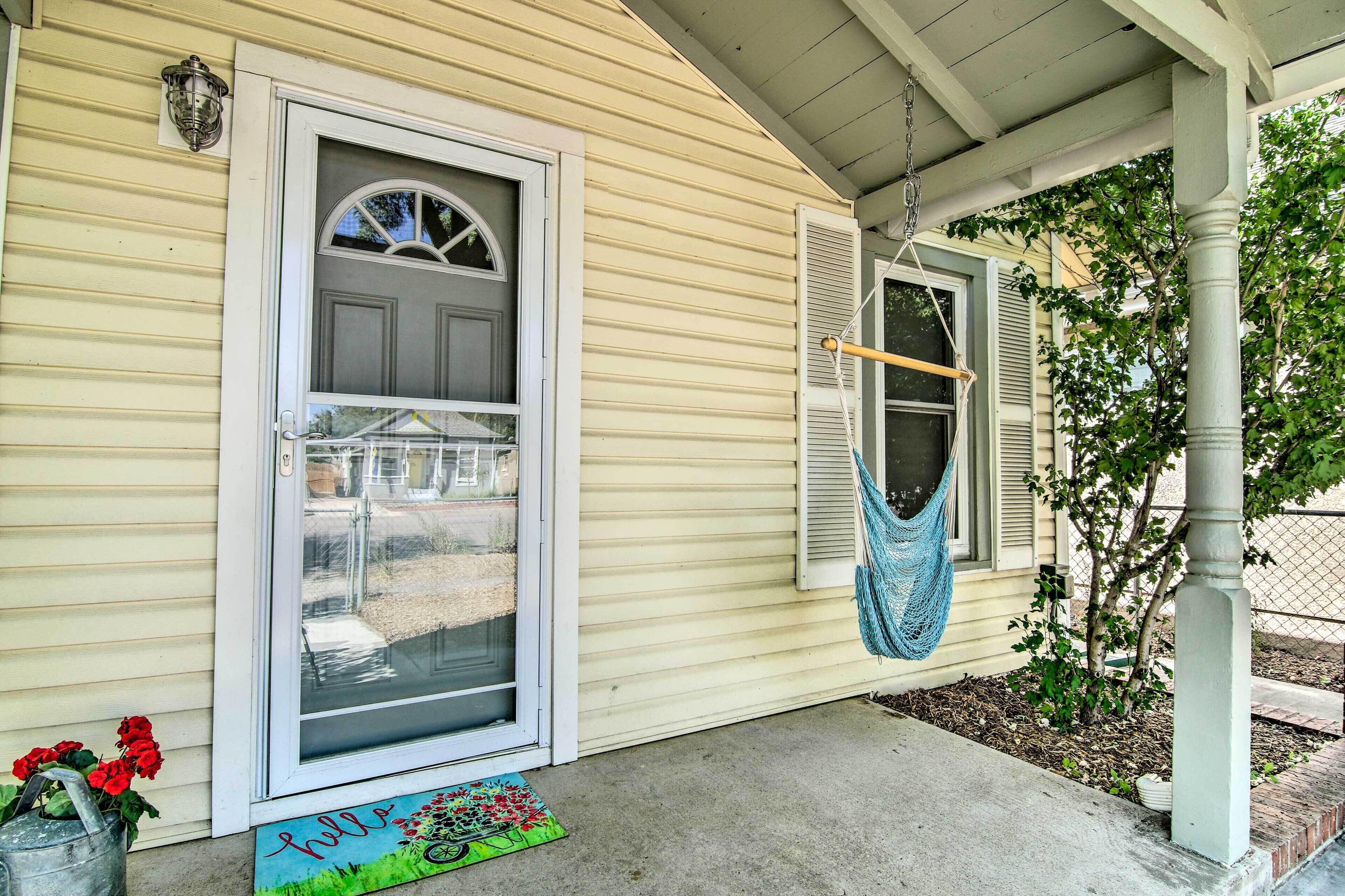 A house with a front door, a window with shutters, a hammock, and a welcome mat.