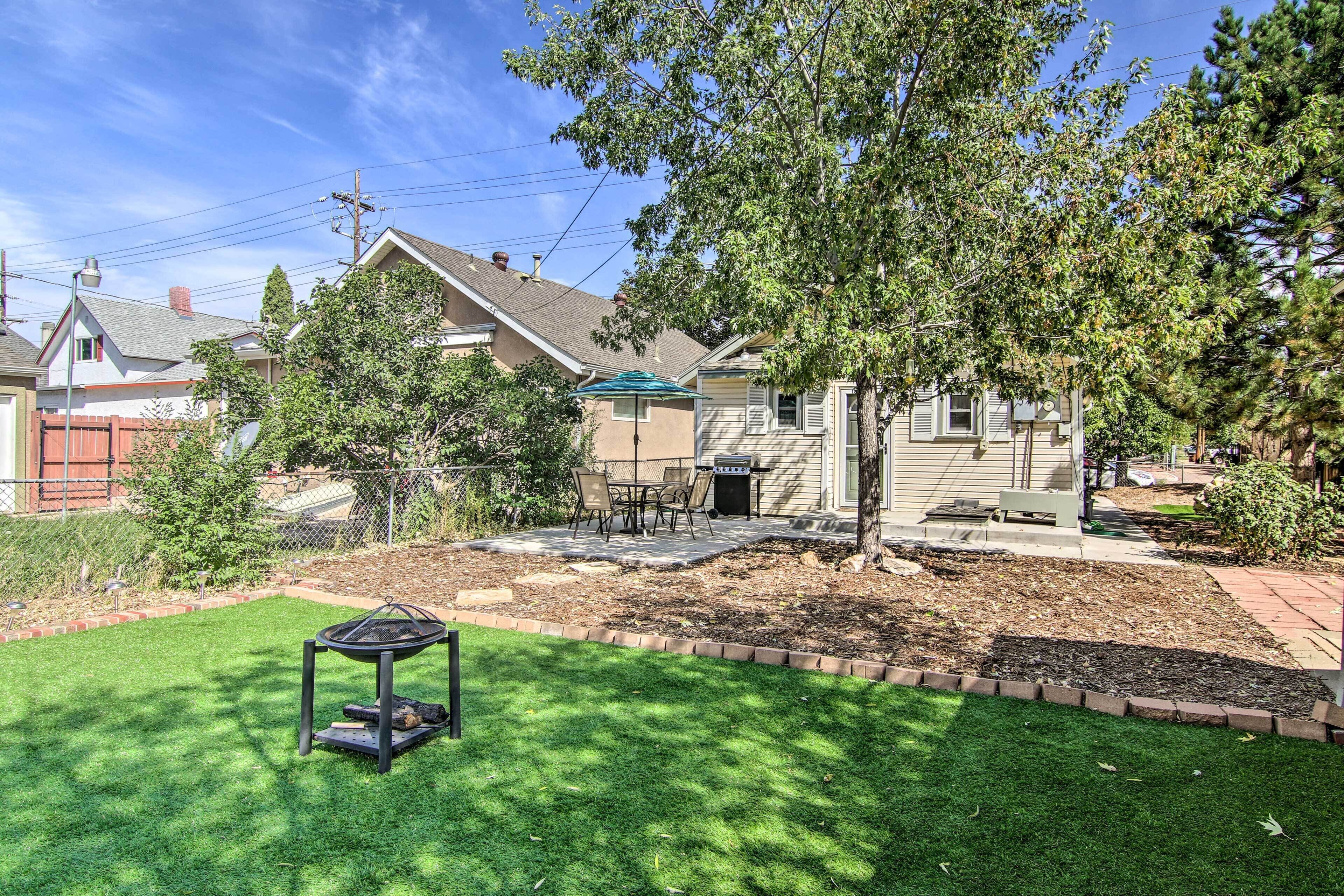A residential backyard with a well-maintained lawn, a barbecue grill, and a patio area.