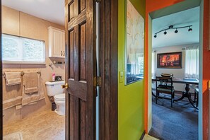 Un baño con inodoro, lavamanos y ventana con persianas.