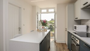 A modern kitchen with a central island, a microwave, and a dishwasher. - Swn Y Mor / Sound of the Sea (Criccieth)