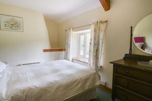 A bedroom with a bed, dresser, window with curtains, and a mirror. - Riverbank (Axminster)