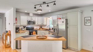 Une cuisine moderne avec des armoires blanches, des appareils en acier inoxydable et un îlot central en bois.