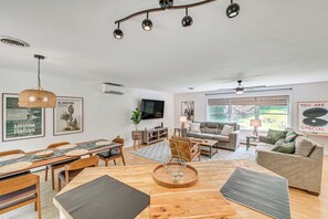 A modern living room with a dining area, a sofa, a TV, and artwork on the walls. - Family-friendly Saugerties Home w/ Hot Tub & Games (Saugerties)