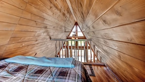 Una camera da letto in una casetta di legno, con un letto, una finestra e una ventola a soffitto.