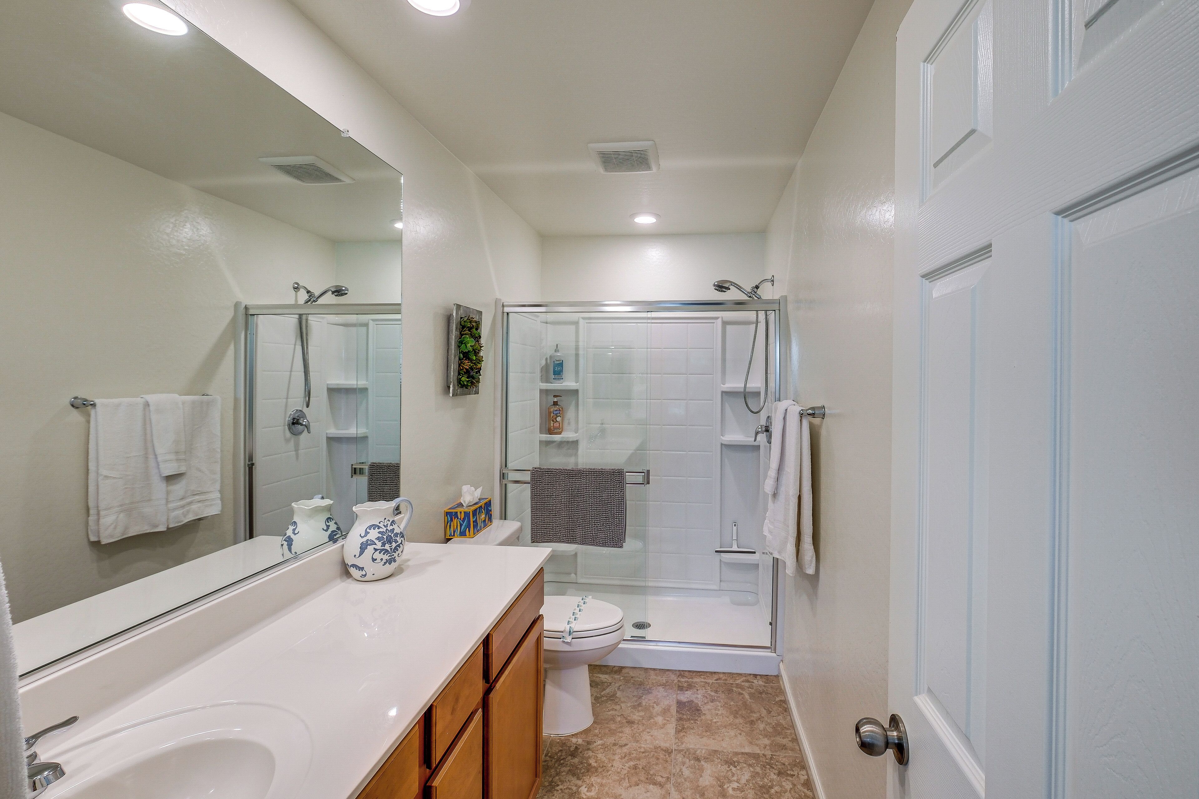 Une salle de bain moderne avec une douche à parois de verre, un lavabo blanc et un grand miroir.