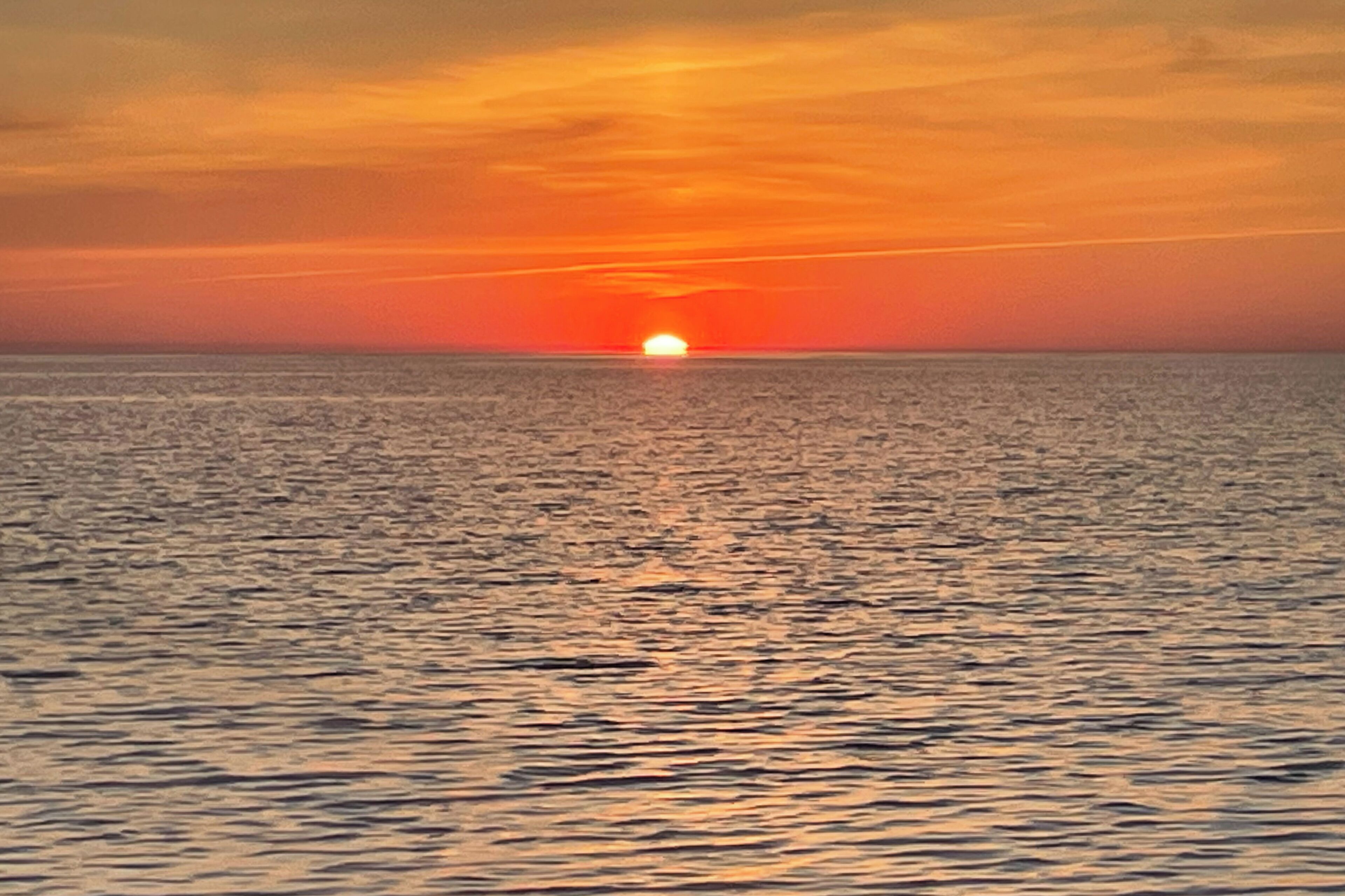 Un coucher de soleil sur une mer calme.