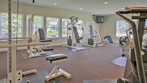 A gym with various exercise machines, mats, and a fan.