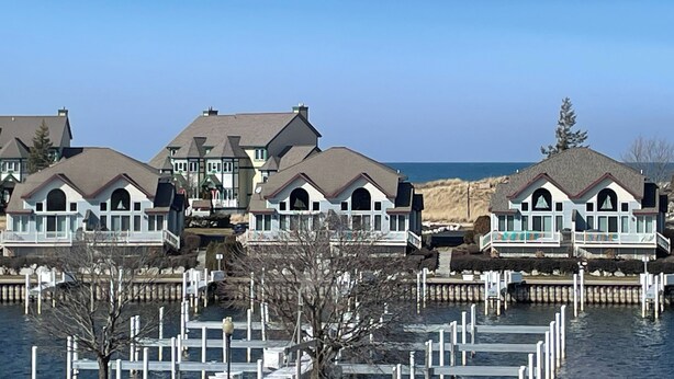 A waterfront property with multiple houses, docked boats, and a clear view of the water.