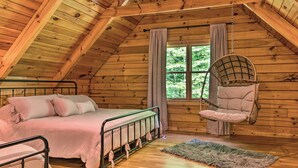A cozy cabin bedroom with a bed, a hanging chair, and a large window. - 7 Mi to Ski Slopes: Mars Hill Cabin w/ Hot Tub! (Mars Hill)