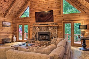 A log cabin interior with a stone fireplace, wooden walls, and a large TV mounted above it. - 7 Mi to Ski Slopes: Mars Hill Cabin w/ Hot Tub! (Mars Hill)