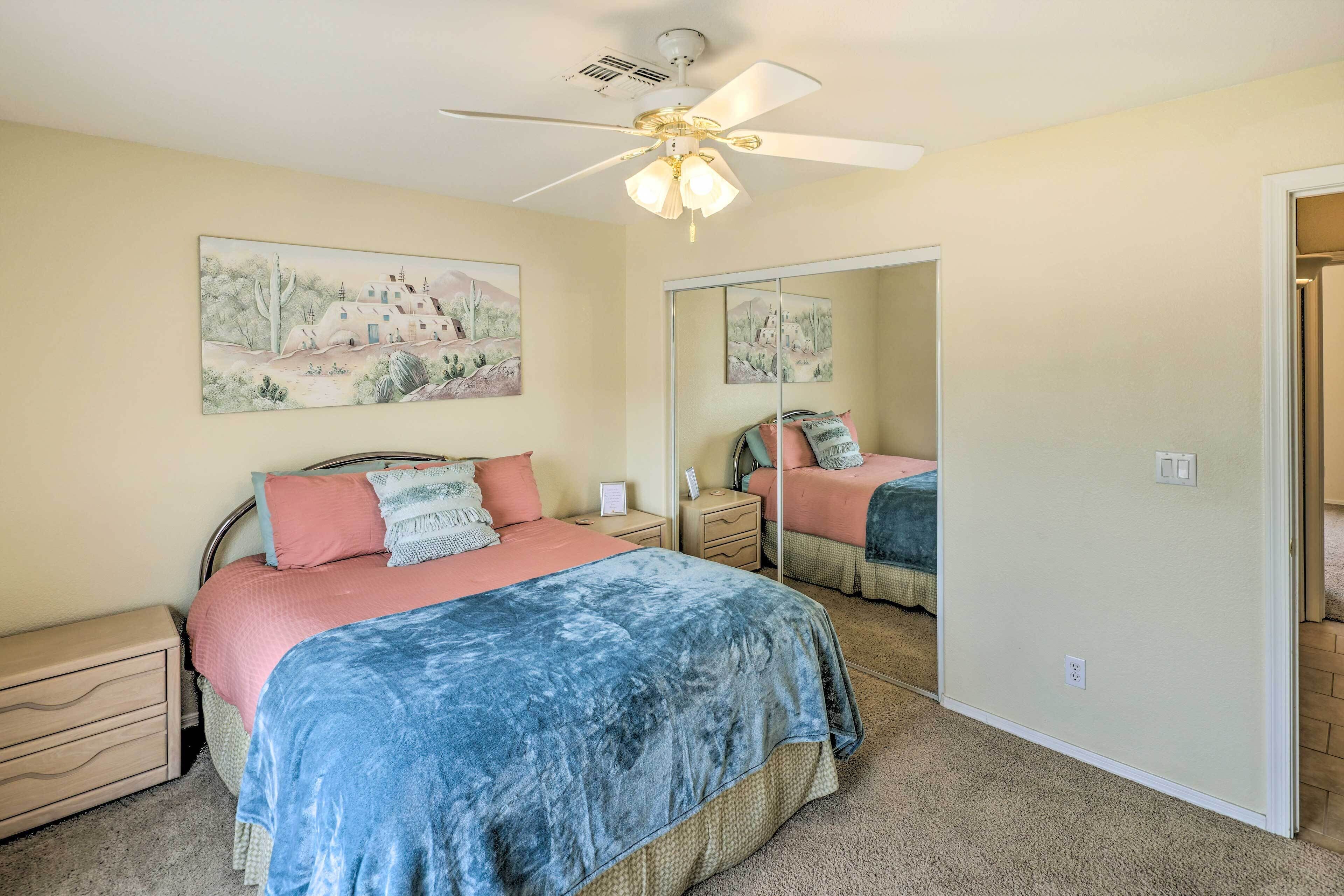 A bedroom with a bed, nightstands, a ceiling fan, and a large mirror.