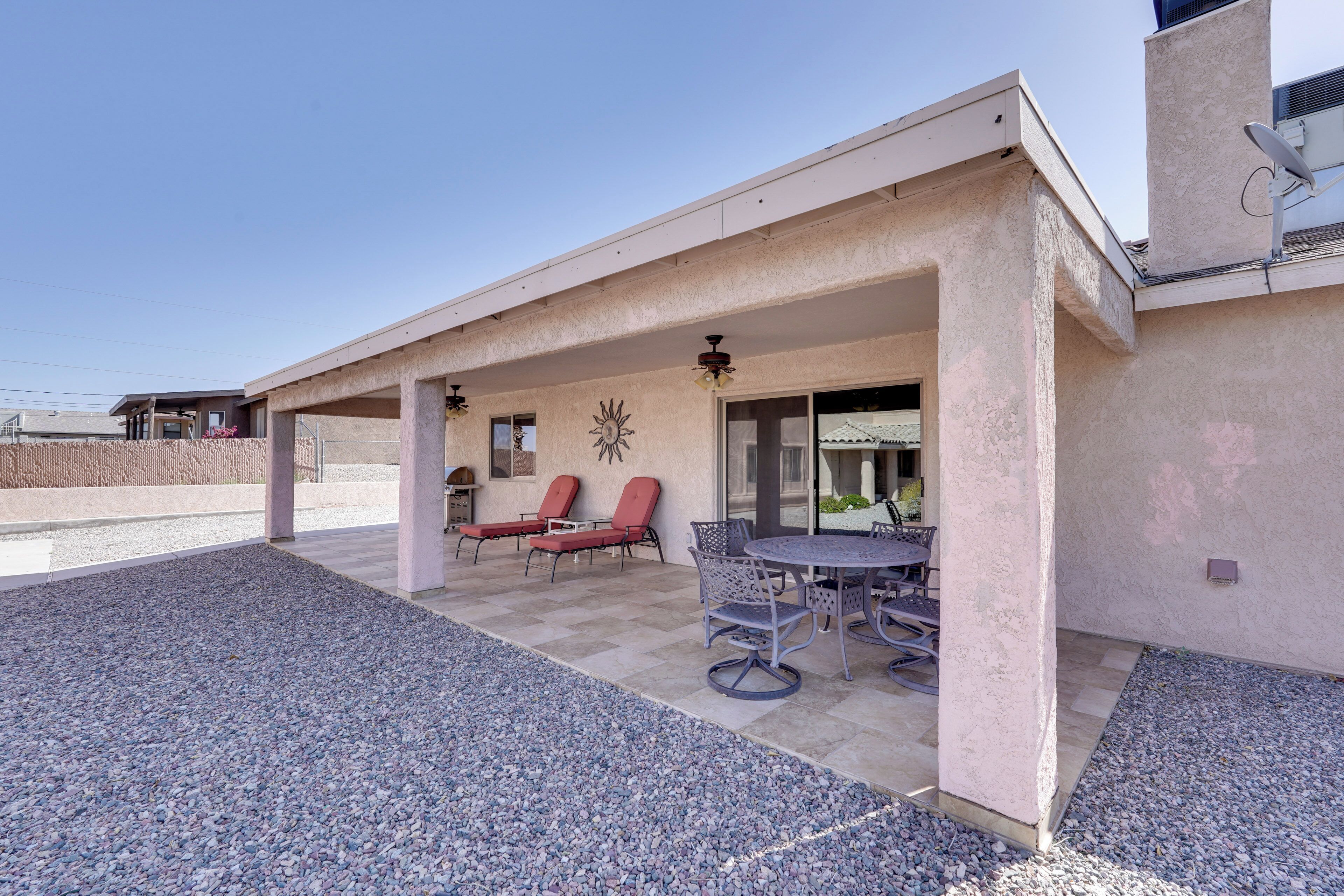 A covered patio with outdoor furniture, a dining table, and a barbecue grill.