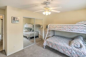 Ein Schlafzimmer mit Etagenbetten, Deckenventilator, Spiegel und Wanduhr.
