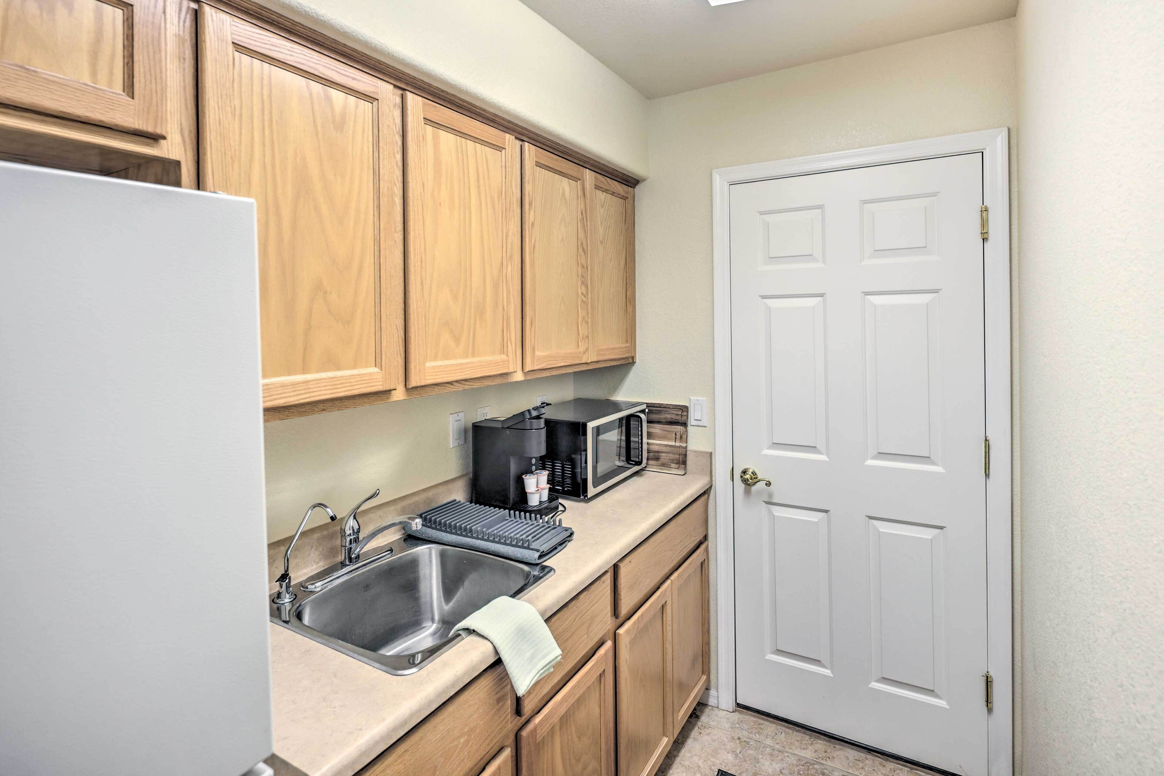 A kitchen with wooden cabinets, a stainless steel sink, a microwave, and a coffee maker.