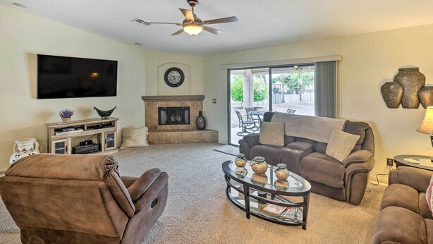 A living room with a fireplace, a ceiling fan, and a large window. - Arizona Retreat w/ Casita ~ 2 Mi to Lake Havasu (Lake Havasu City)