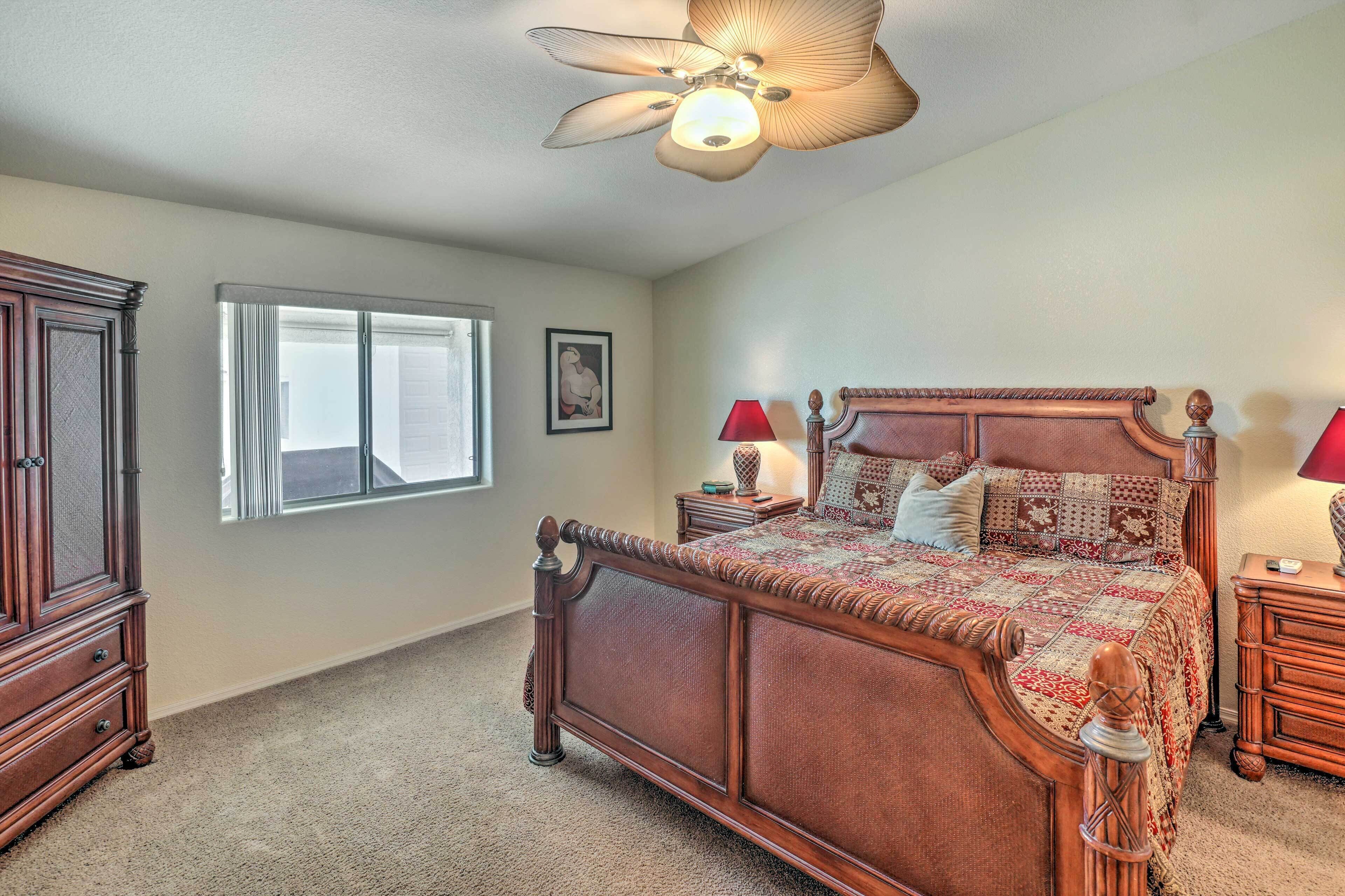 A bedroom with a large bed, a ceiling fan, a window, and a dresser.
