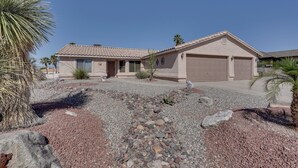 A single-story house with a tiled roof, a garage, and a gravel driveway. - Arizona Retreat w/ Casita ~ 2 Mi to Lake Havasu (Lake Havasu City)