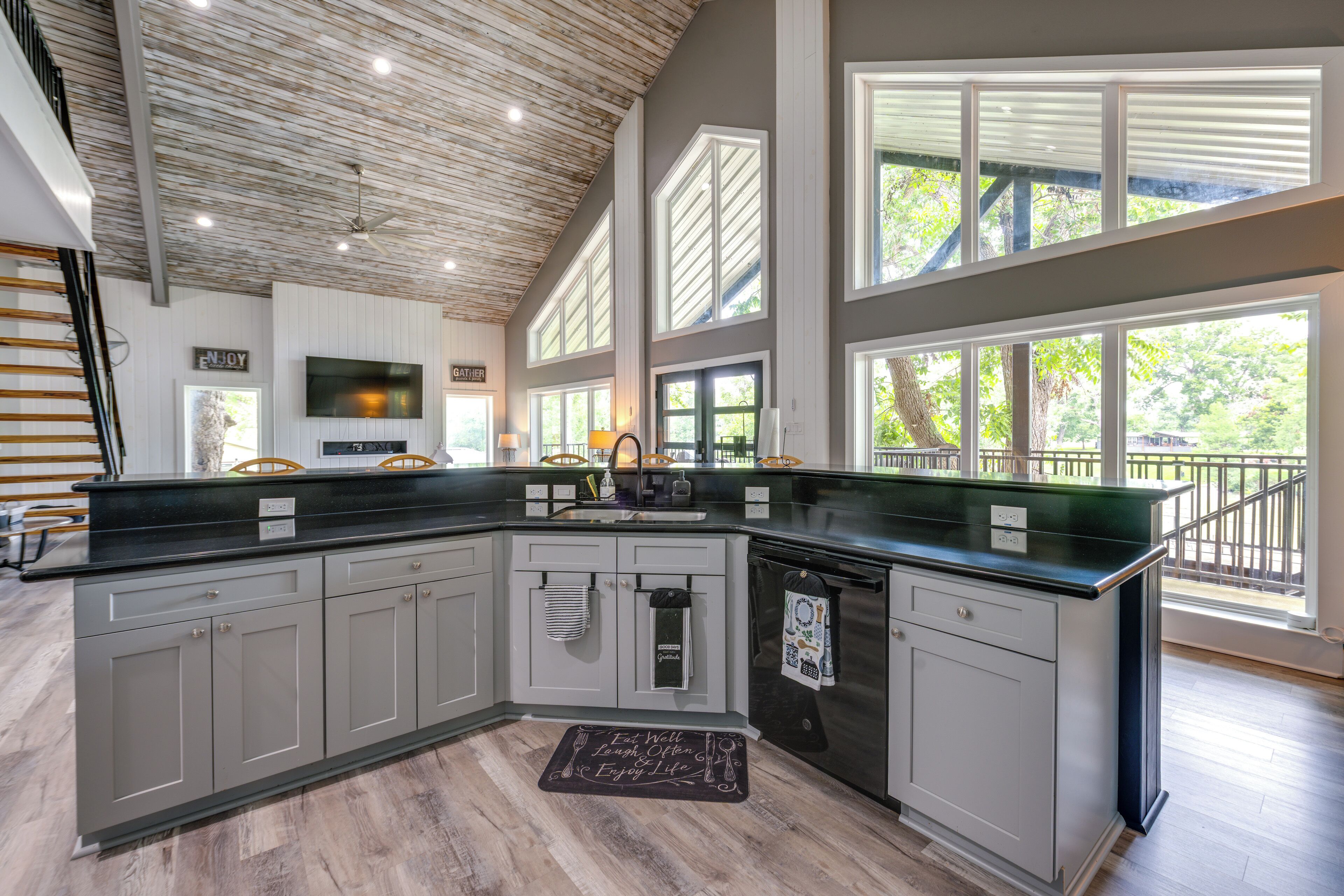A modern kitchen with a large island, built-in appliances, and large windows offering views of the outdoors.