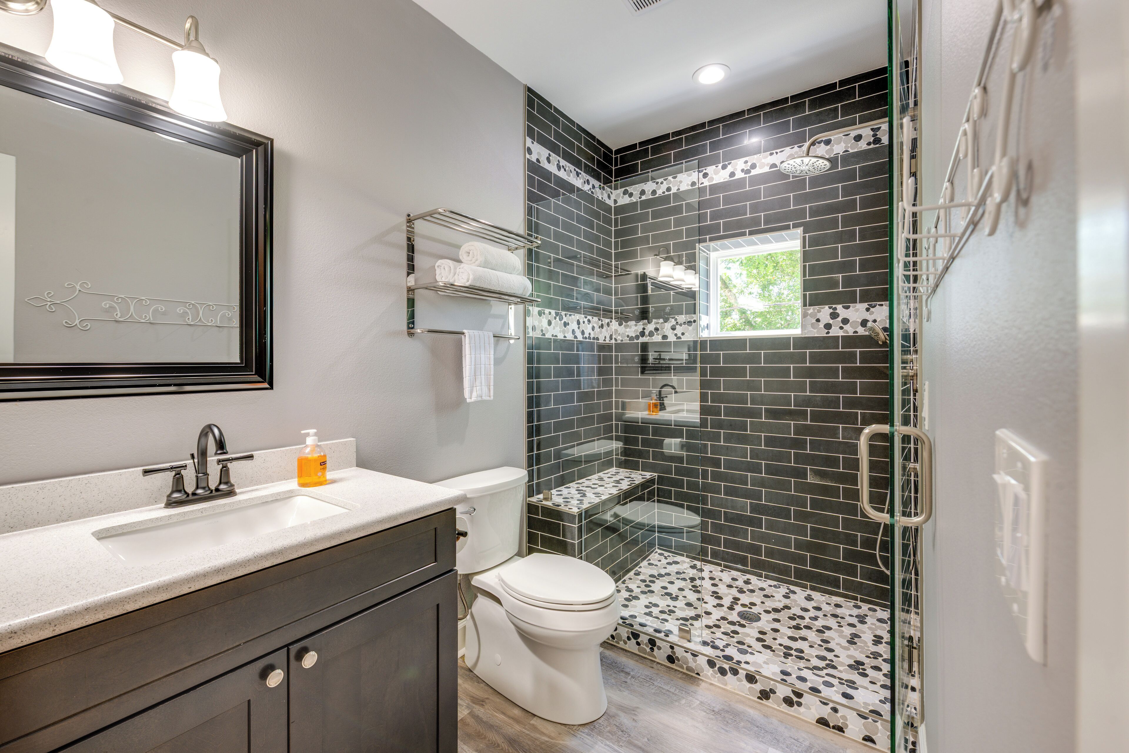 A bathroom with a glass-enclosed shower, a white toilet, a vanity with a mirror, and a sink.