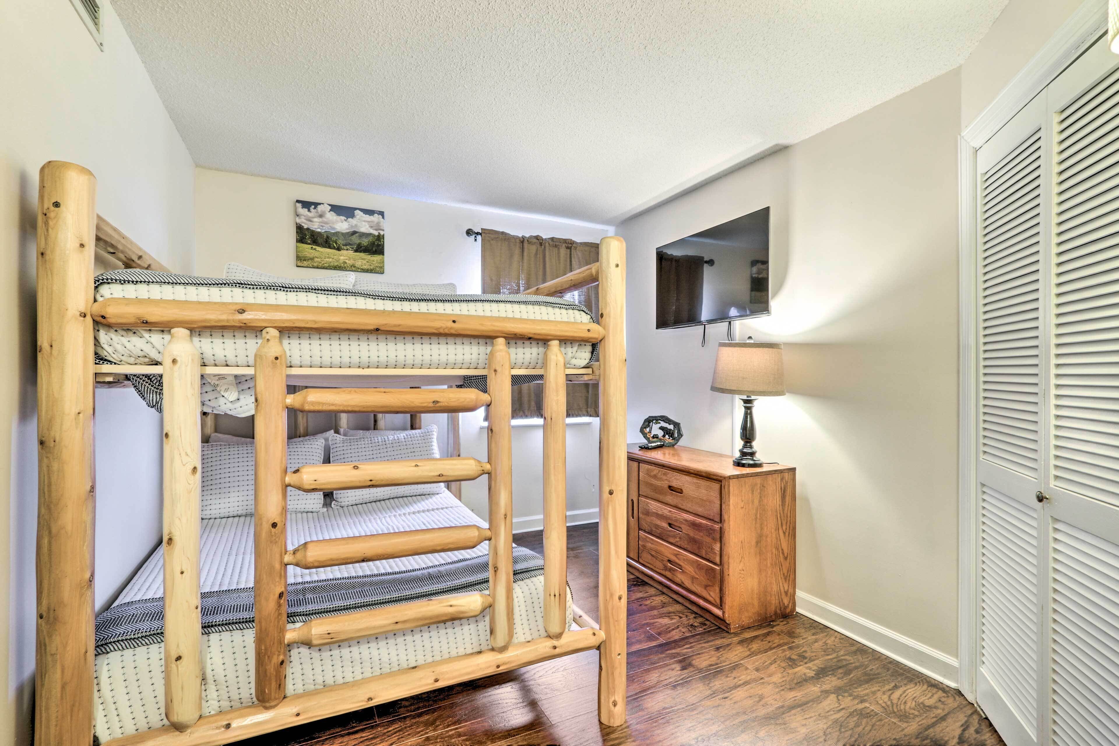 A bunk bed with a wooden frame and a small wooden dresser beside it.