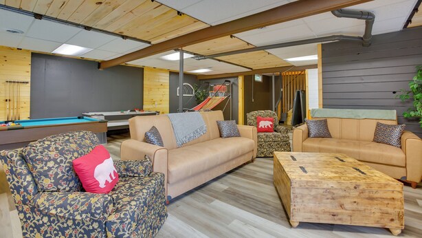 A spacious indoor area with a pool table, two sofas, a wooden coffee table, and a play area with a slide. - Spacious Wellston Home Near Hiking & Skiing! (Wellston)