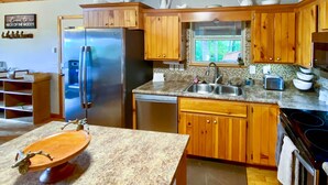 A kitchen with wooden cabinets, a stainless steel refrigerator, a dishwasher, and granite countertops. - Game Room & Fire Pit: Picturesque Cabin in Murphy (Murphy)