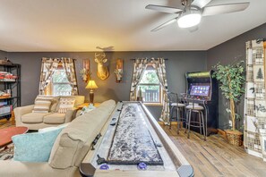 Un salon comprenant une table de jeu de «
shuffleboard
», un canapé, une table basse et un ventilateur de plafond.