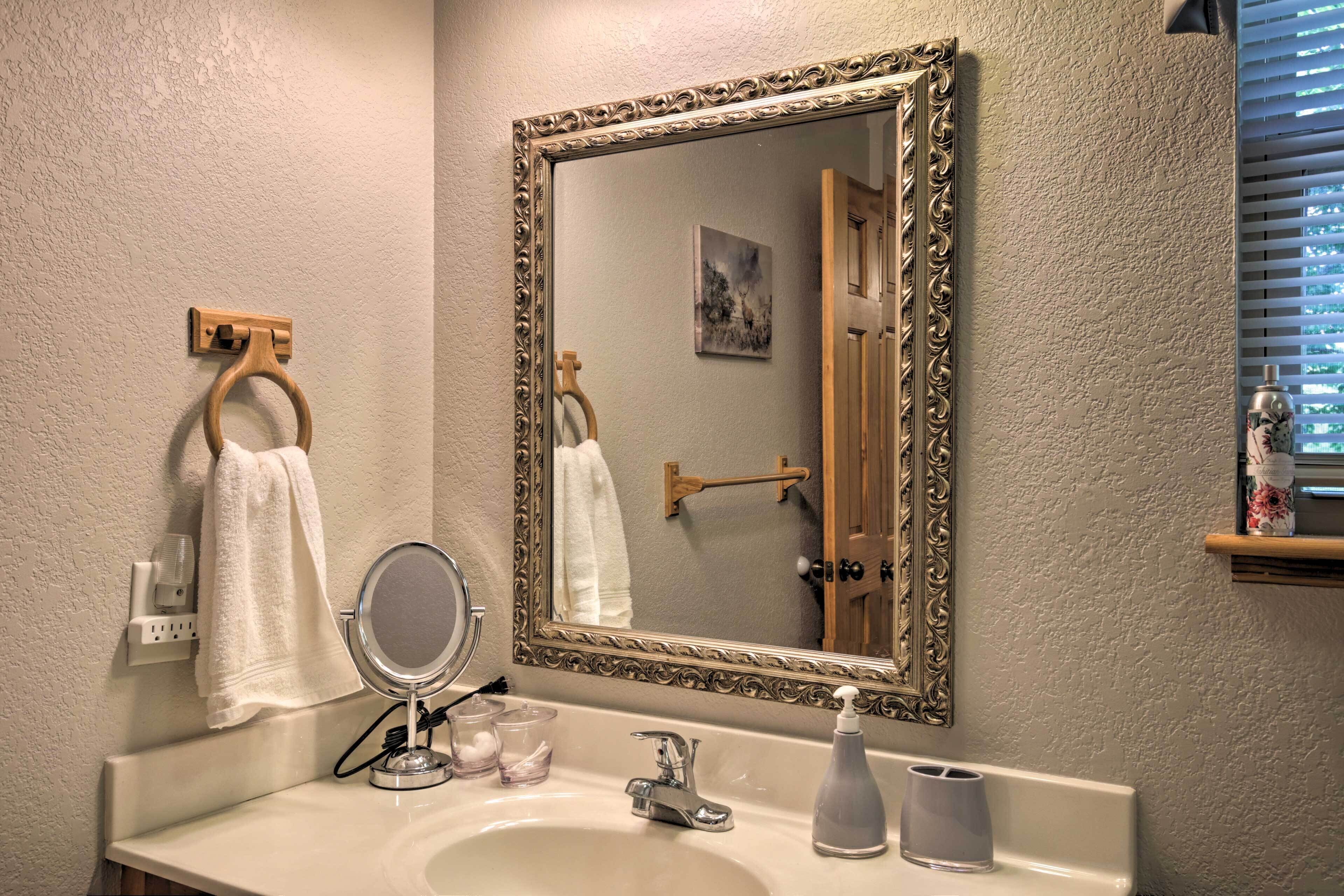 A bathroom with a large mirror, a sink, and a towel rack.