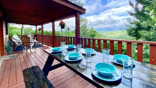 A wooden deck with a table set for four, overlooking a scenic landscape. - Game Room & Fire Pit: Picturesque Cabin in Murphy (Murphy)