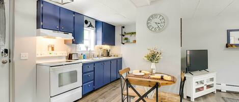 Una cocina moderna con armarios azules, una estufa blanca y un comedor con mesa y sillas de madera.