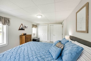 A bedroom with a large bed, a dresser, and two doors. - Chic & Central Apartment ~ 6 Mi to Sebec Lake! (Dover-Foxcroft)