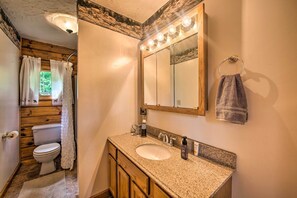 A bathroom with a wooden vanity, a sink, a mirror with lights, and a towel hanging on the wall. - Cozy Family-friendly Pine Grove Cabin w/ Fire Pit! (Pine Grove)