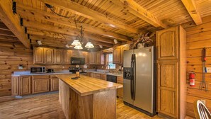 A wooden cabin-style kitchen with a central island, wooden cabinets, and a stainless steel refrigerator. - Cozy Family-friendly Pine Grove Cabin w/ Fire Pit! (Pine Grove)
