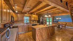 A spacious kitchen with wooden cabinetry and a large island, featuring a sink, stove, and refrigerator. - Cozy Family-friendly Pine Grove Cabin w/ Fire Pit! (Pine Grove)