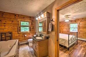Un baño de cabaña de madera con bañera, lavamanos y cama.