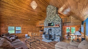 A cozy cabin interior with a stone fireplace, wooden floors, and a balcony overlooking a scenic view. - Cozy Family-friendly Pine Grove Cabin w/ Fire Pit! (Pine Grove)