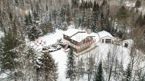 A cabin surrounded by snow-covered trees, with a deck and outdoor seating area.