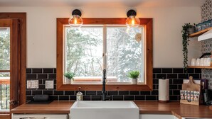 A modern kitchen with a large window, wooden cabinets, and a built-in dishwasher.
