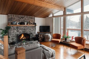 A cozy living room with a stone fireplace, a flat-screen TV, and comfortable seating.