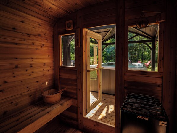 A wooden cabin interior with a bench, a window, and a Harvia wood stove.