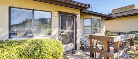 A house with a patio area, a door, and a window with blinds.