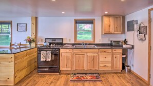 Une cuisine avec des meubles de rangement en bois, une cuisinière, un évier et une fenêtre.