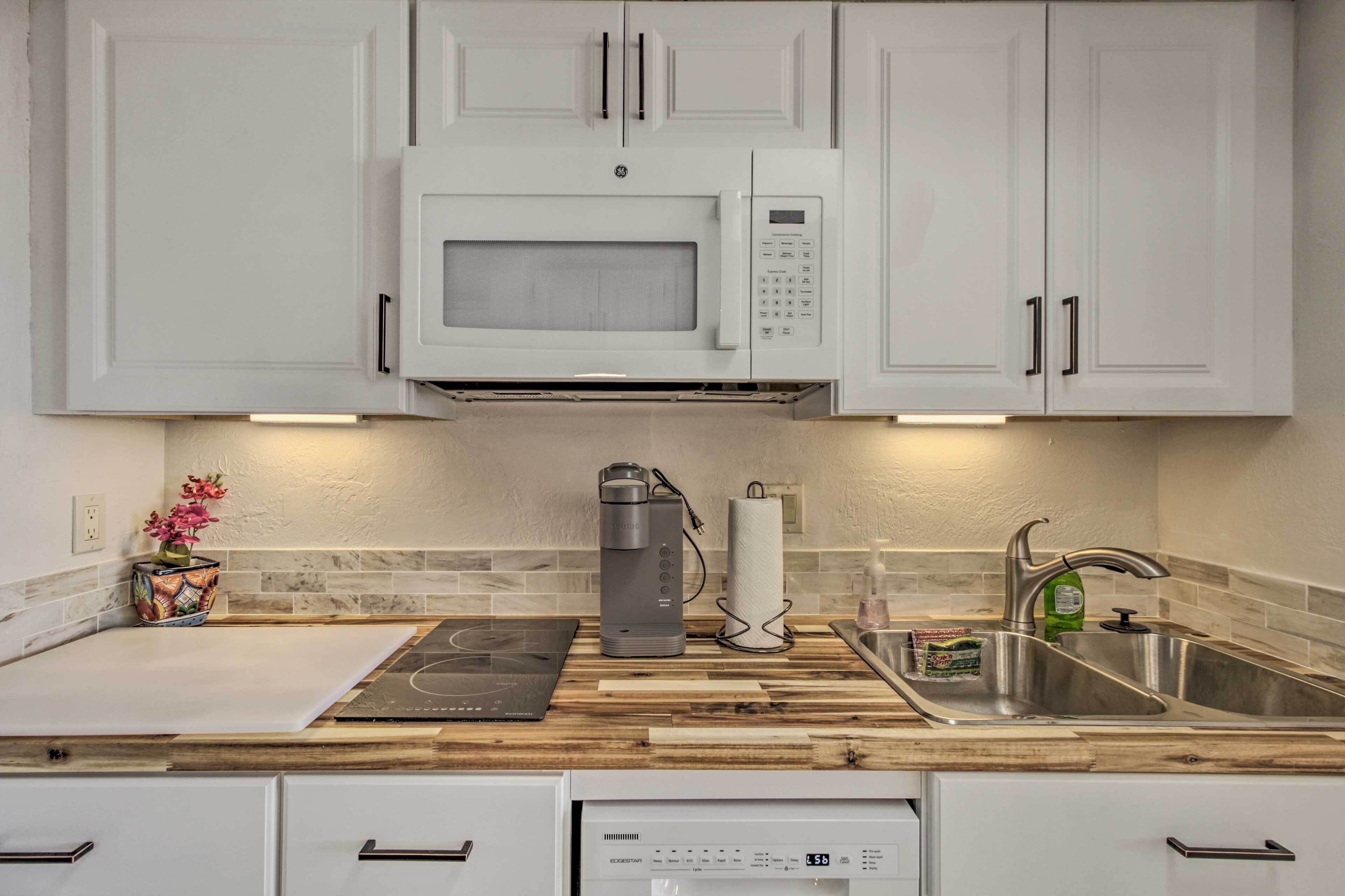 A kitchen with white cabinets, a built-in microwave, a coffee maker, a sink, and a dishwasher.