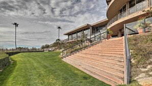 A modern building with a curved balcony, a staircase leading to the entrance, and a well-maintained lawn. - Near Golf: Mtn-view Studio in Tucson! (Tucson)